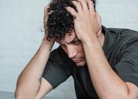 pexels-photo-8560849-8560849 Man sitting at table looking stressed with hands on head, emotional expression.